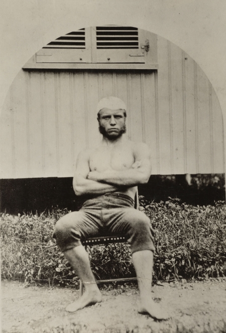 Teddy Roosevelt sits in a chair while wearing sculling gear. At this time, about 1877, he was an an undergraduate at Harvard.