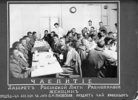 Men have tea around crowded tables at the infirmary of the Russian League for Women's Equal Rights, 1916