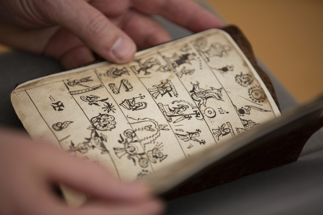 someone handling a small book with illustrations