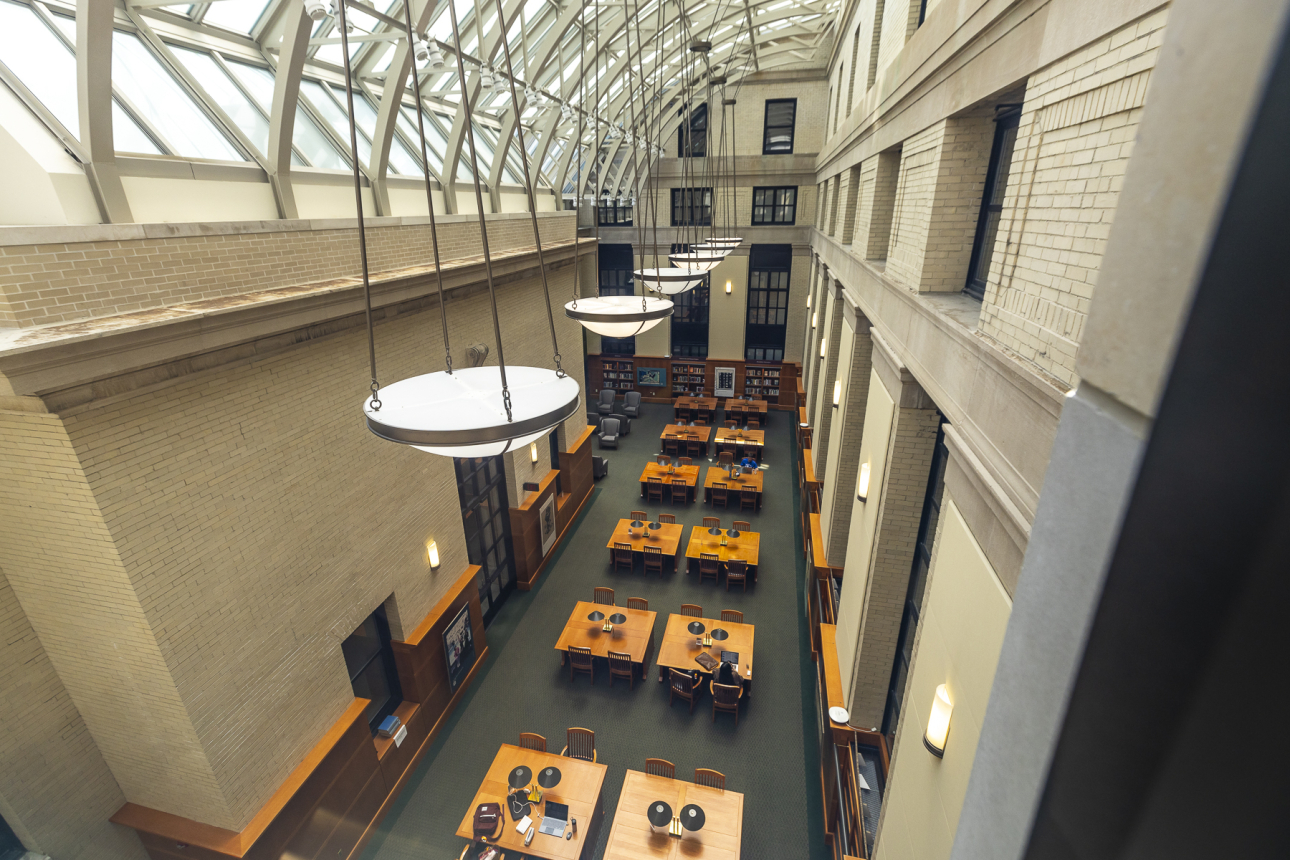 A view of the Phillips Reading Room from above, which shows several four-seat desks and light pouring in from the skylights