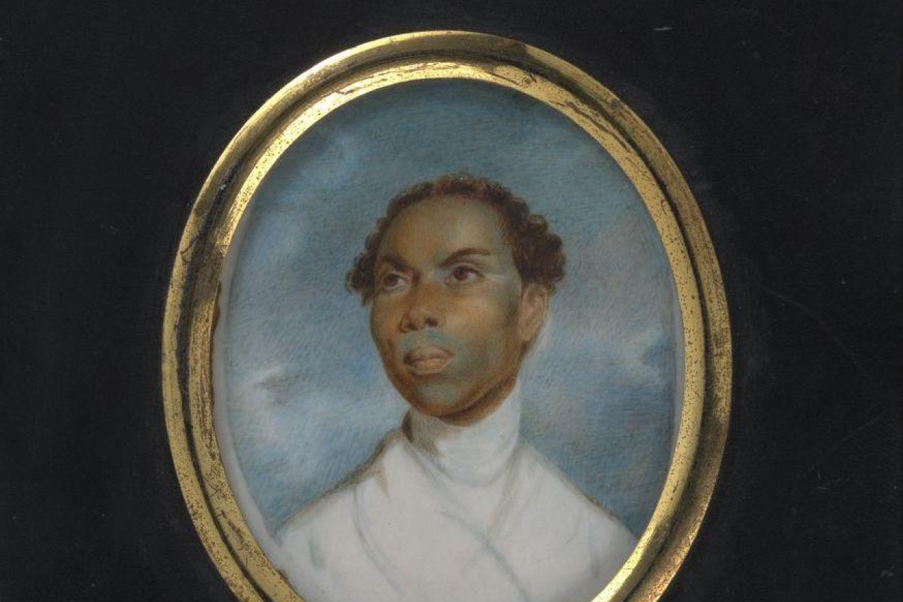 Black man with short curly hair, wearing a white garment