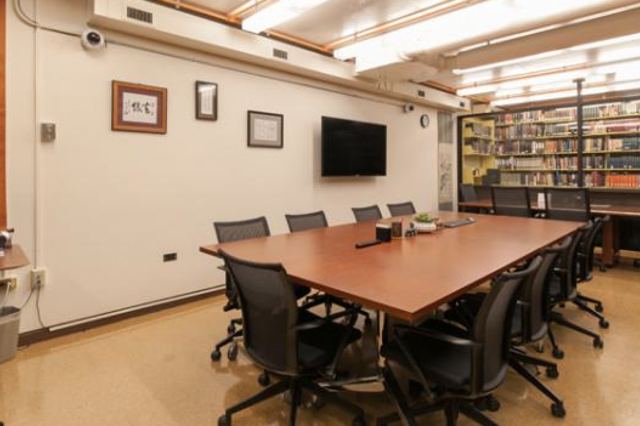 A room is seen with a large table surrounded by chairs.