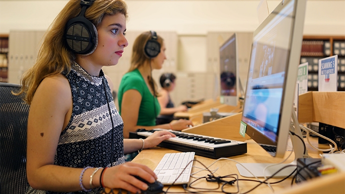 Students wearing headphones work at computers