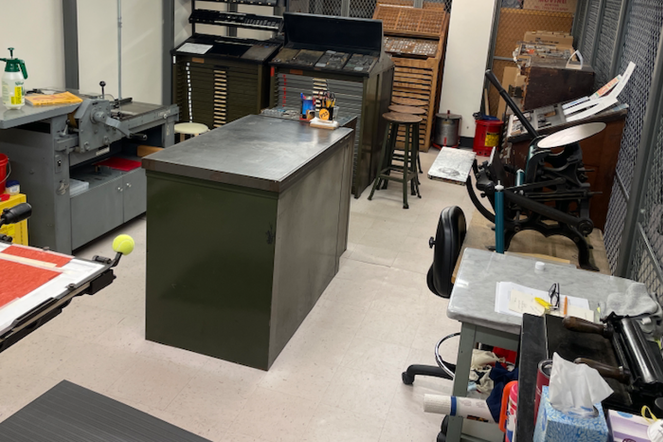 printing studio in Lamont Library with a work table, iron hand press, Vandercook proof press, and drawers of type and ornaments