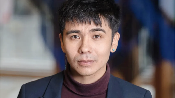 Author Ocean Vuong in center of photo wearing burgundy turtleneck and navy blazer