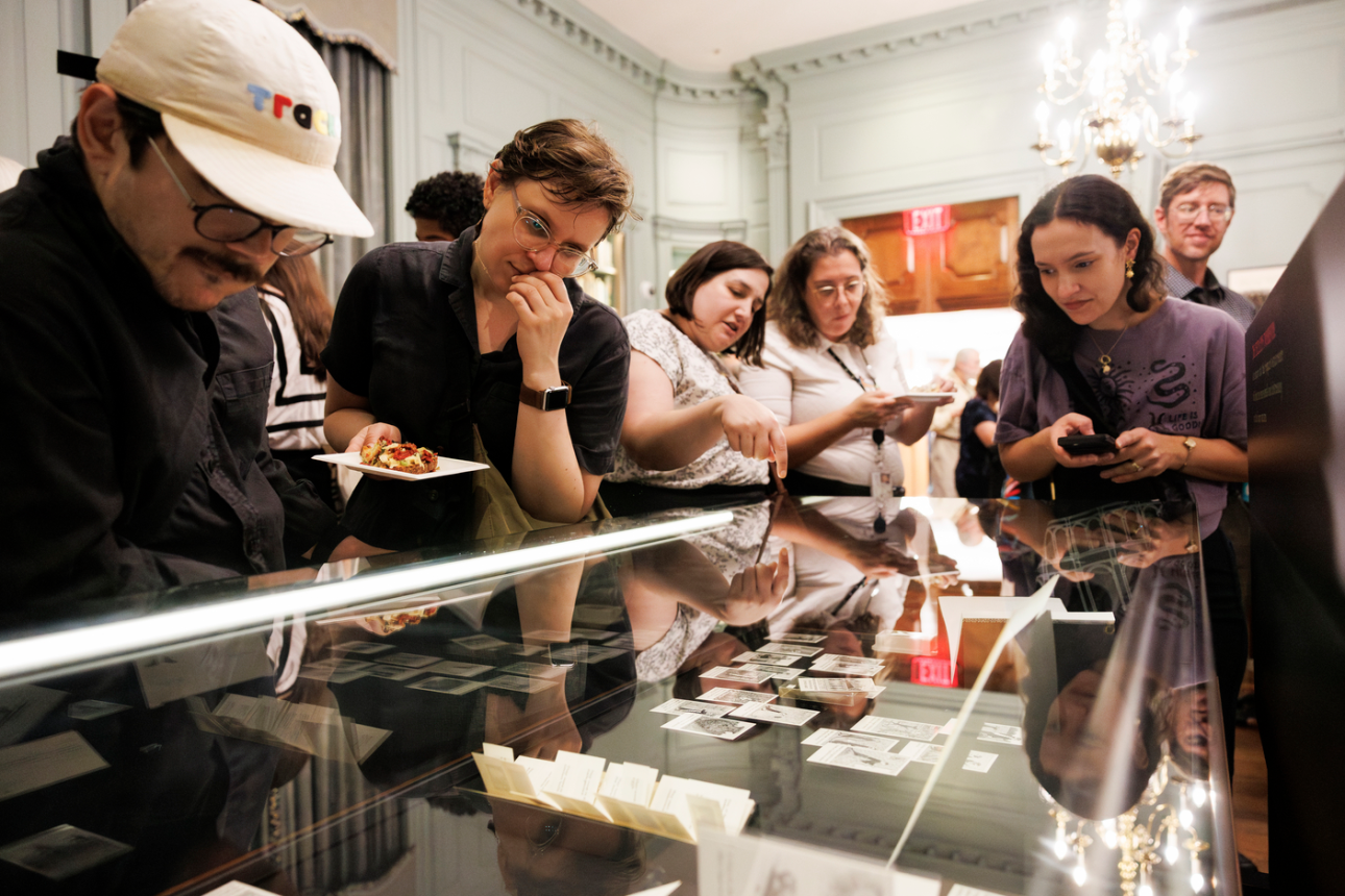 Event attendees view materials in a case during an opening for a Houghton Library Exhibit