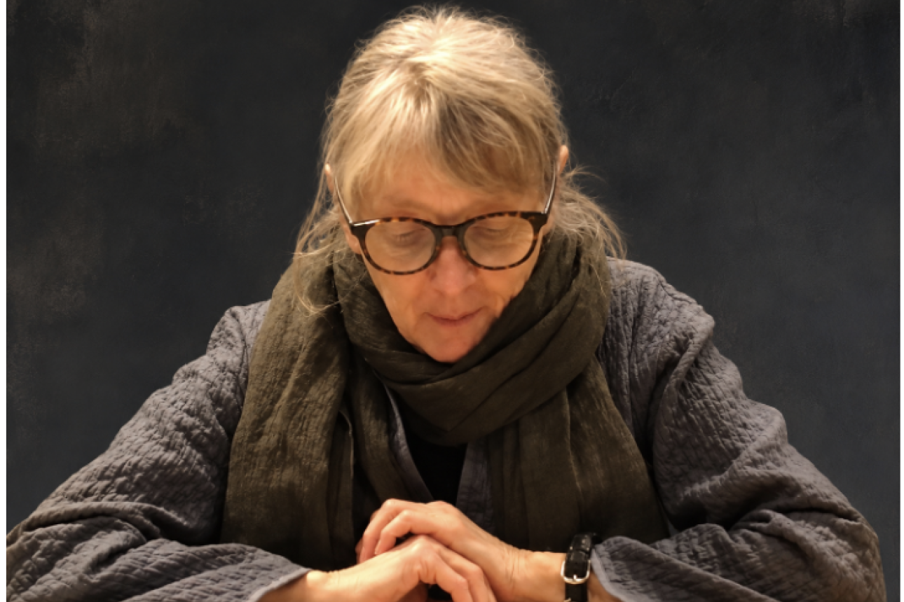 Fanny Howe headshot with arms crossed over a book she is reading