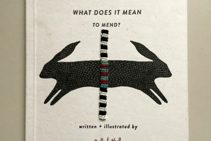 Photo of a book that includes an illustration of black rabbits and a beaded band