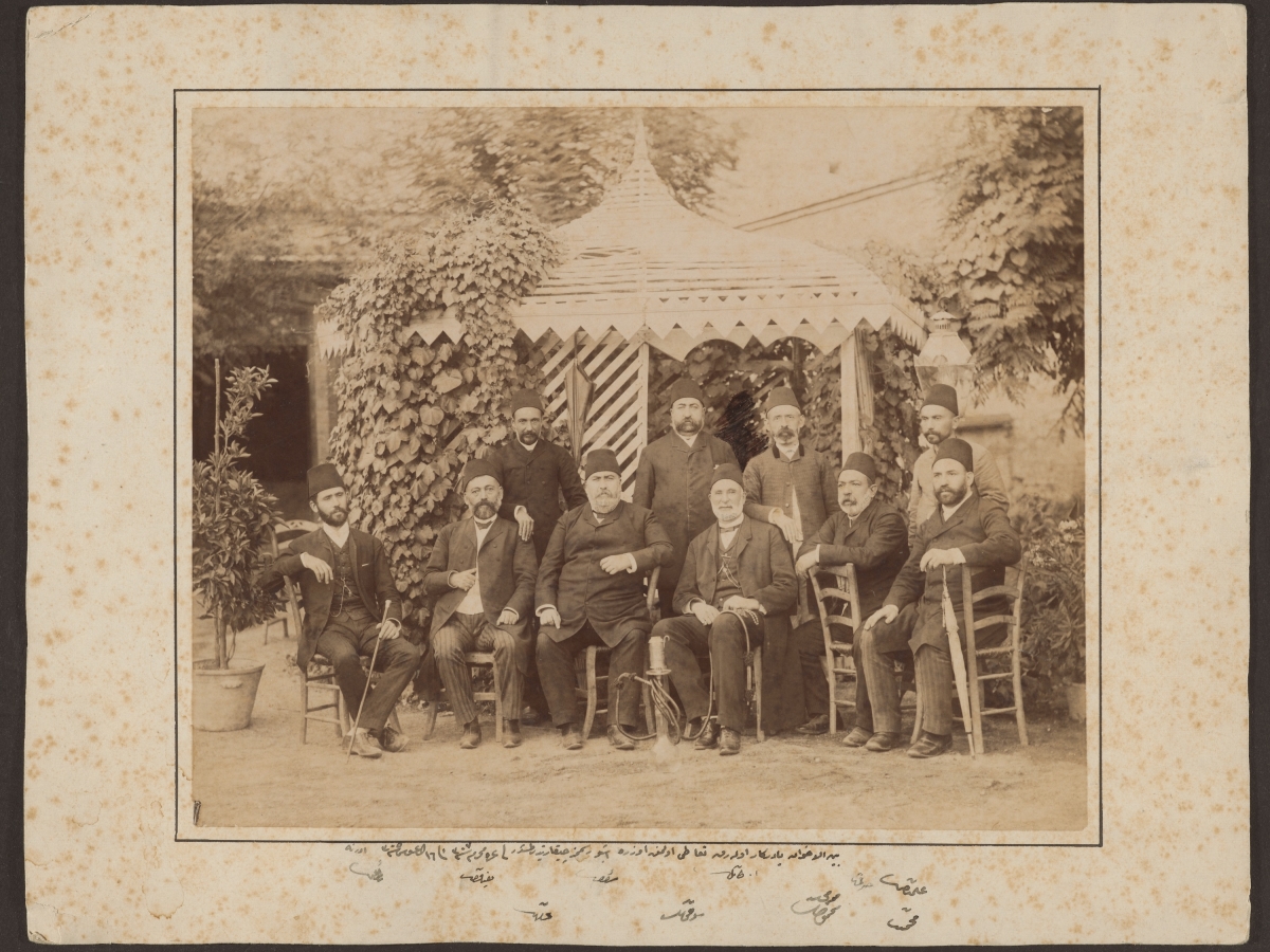 Sepia toned black and white photograph of a group of men in front of a tent outside