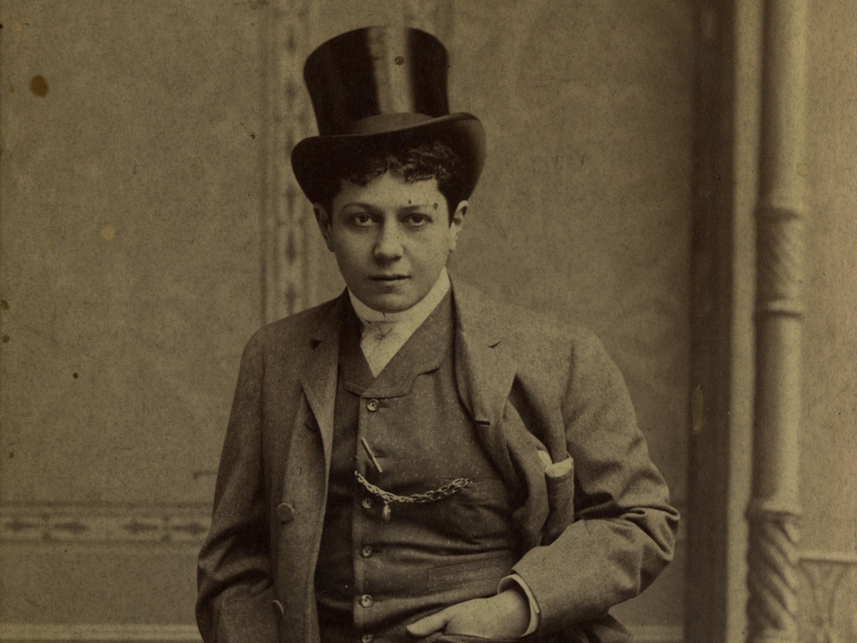 Woman with short curly hair in top hat, waistcoat, and tailcoat.