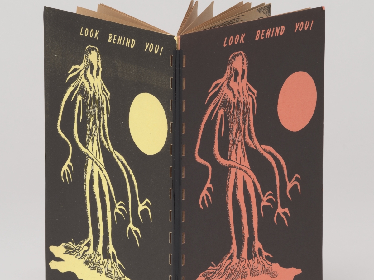 A book with a plastic spiral binding with both covers depicting a chthulu, full moon, and the title "Look Behind You!"
