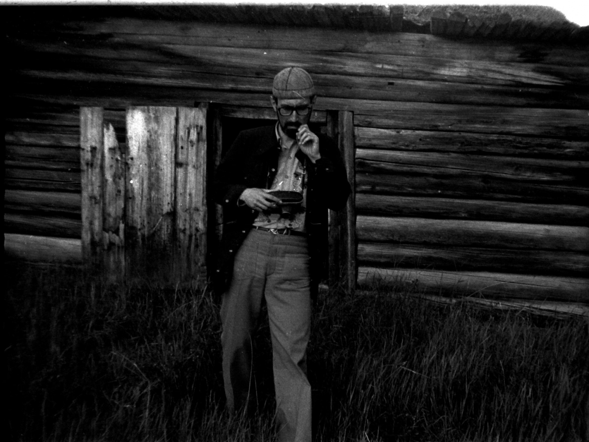 Black-and-white photograph of Siberian-born ethnomusicologist Eduard Alekseyev holding a recording device as he leans against a wooden structure