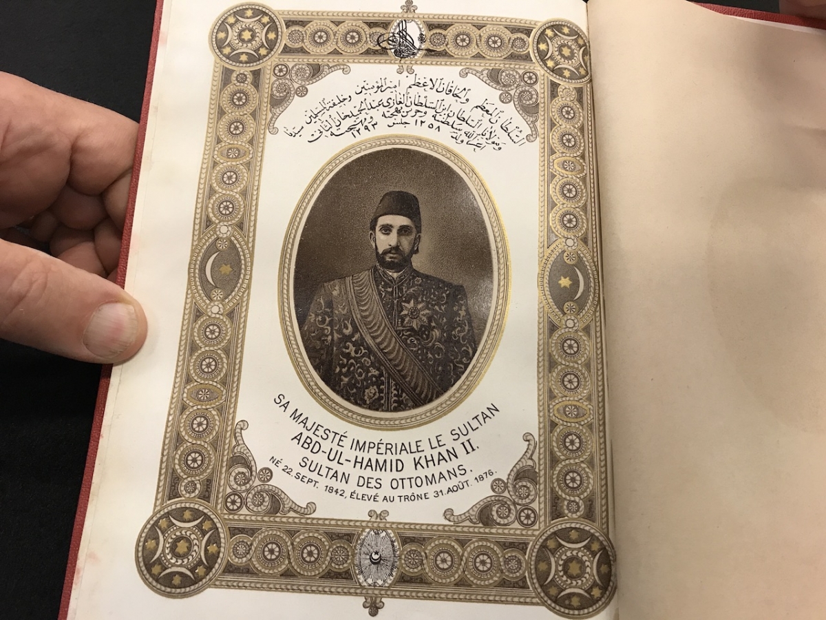 hand holding a photograph of a man in a fez