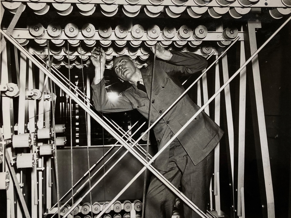 Howard Aiken working on the Mark I Computer, as he looks up and tinkers with parts in the dark
