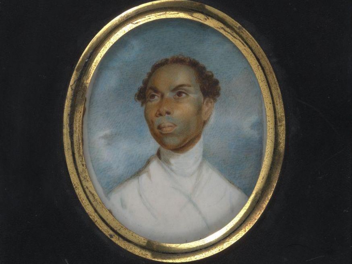 Black man with short curly hair, wearing a white garment