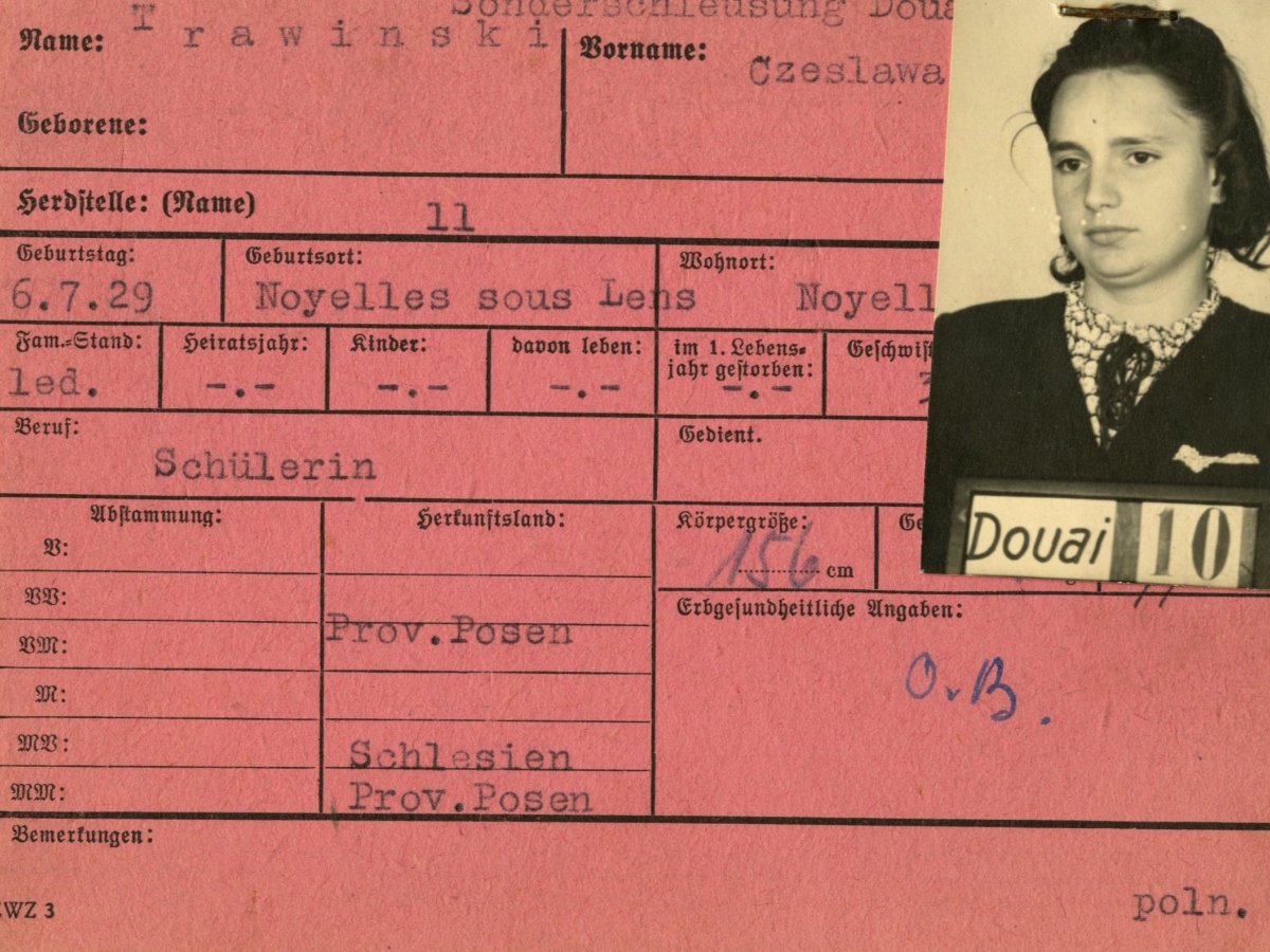 Pink identity card for Czeslawa Trawinski, a French schoolgirl in Douai, with her black and white photograph stapled in the upper right corner, with typed text describing her physical appearance and ancestry. 