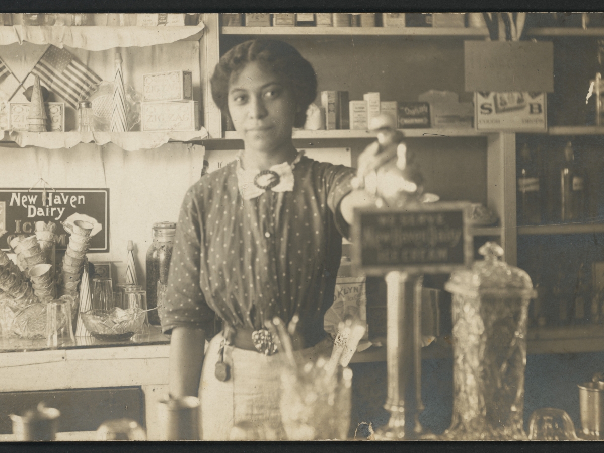 Photograph of pharmacist Anna Louise James behind the soda fountain of the James family pharmacy, 