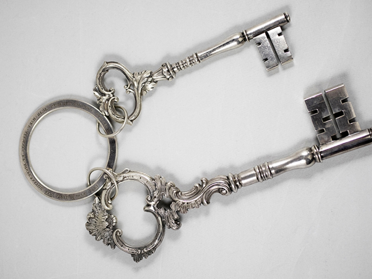 Two silver keys on a silver ring against a white background.