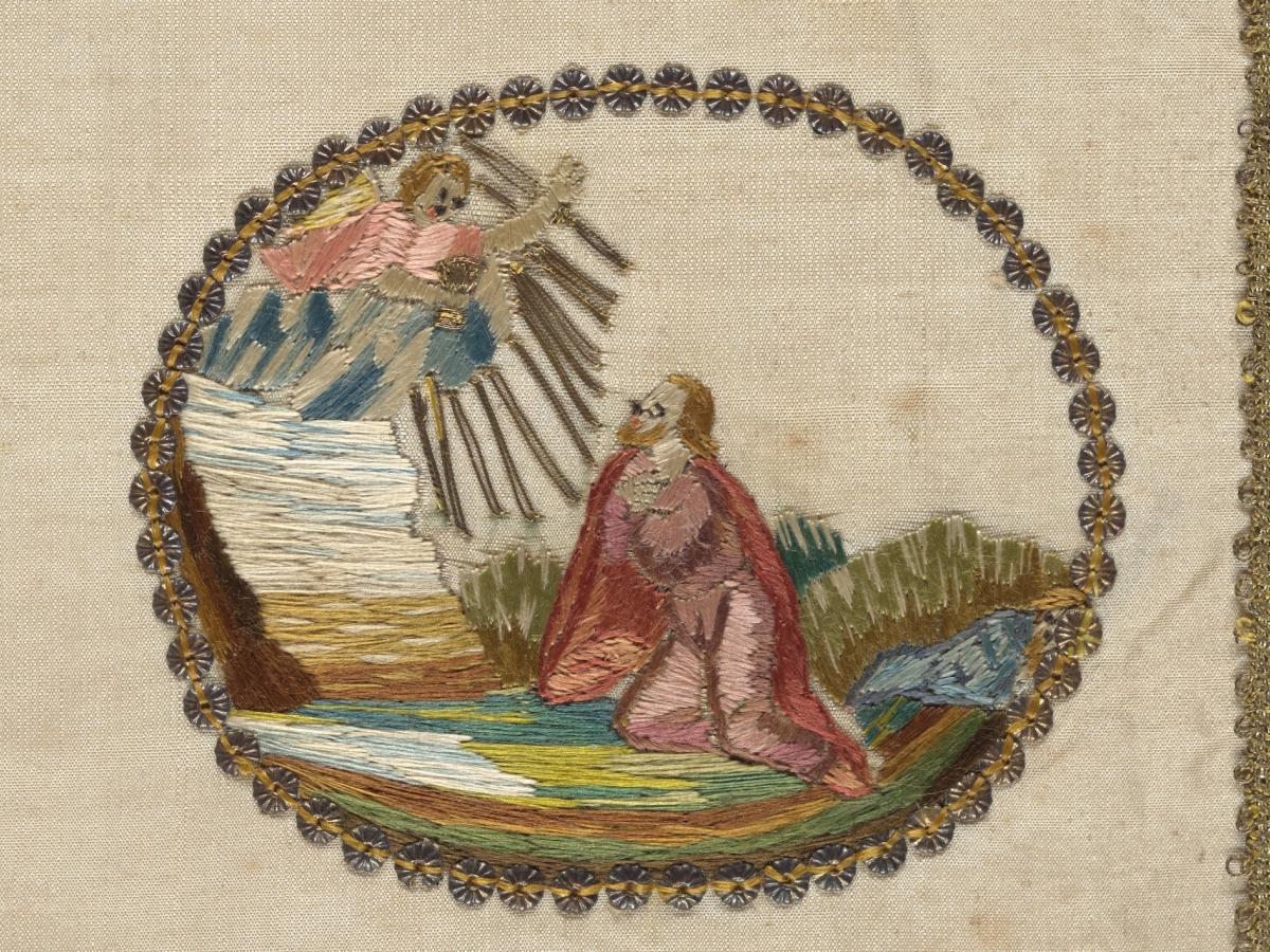 Embroidered scene of Jesus kneeling in a pink robe, looking up at an angel with a cup, appearing out of a cloud.
