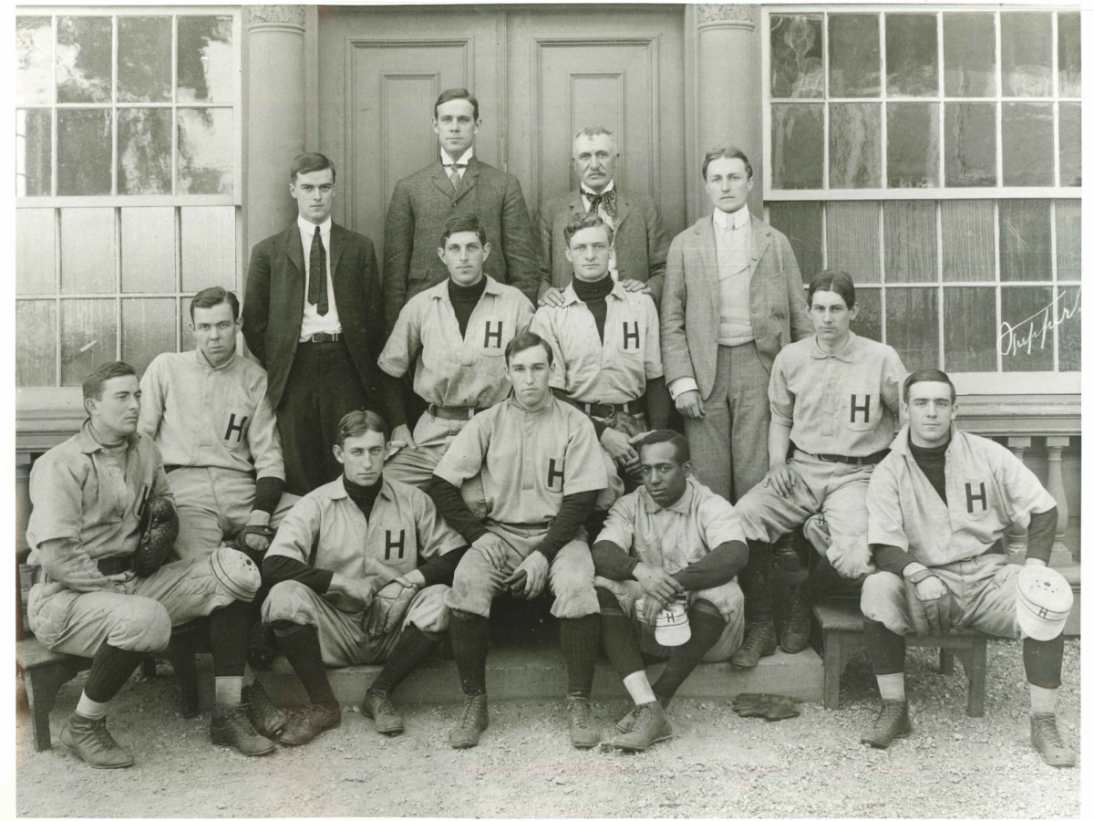 Baseball players and coaches from Harvard's 1905 varsity baseball team pose sitting and standing on a stoop.