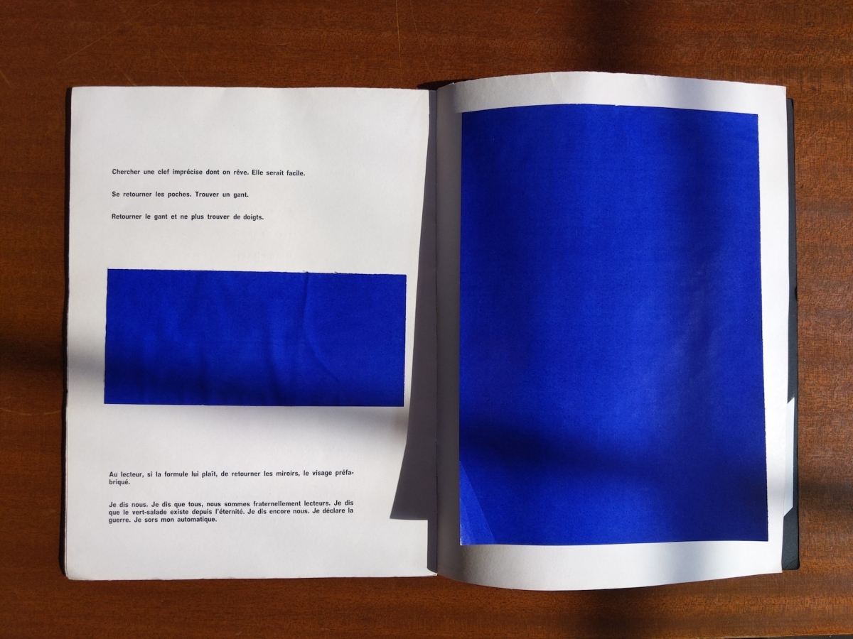 Marcel Broodthaers poetry book with a collage of colored papers over the pages and poems.