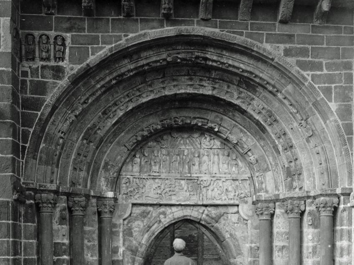 Church at Perse, Espalion (Aveyron), exterior, south side, with Arthur Kingsley Porter studying the sculpted portal and taking notes.