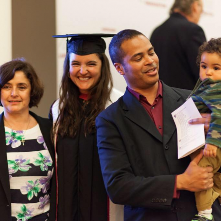 Tania, in graduation attire, standing with her family
