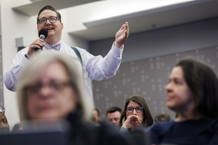 A photo of Kyle Courtney standing and speaking with a mic in a conference hall