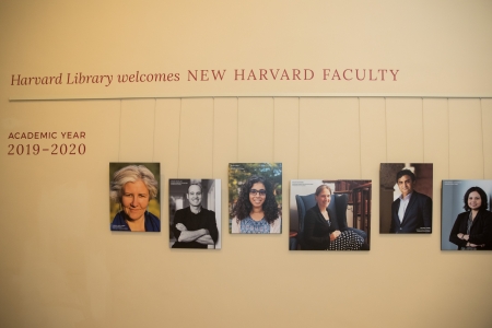 Portraits hanging on a wall under the title 'Harvard Library Welcomes New Harvard Faculty'