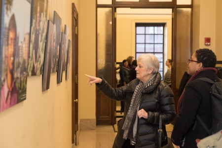 Two Harvard deans view new faculty exhibit in Widener Library hallway.