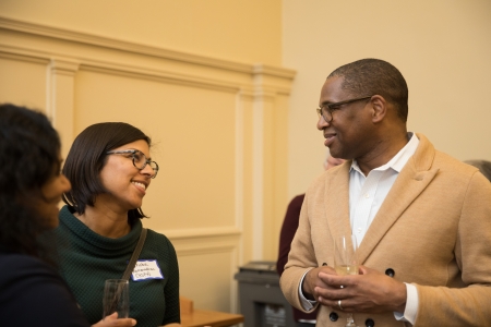 Female faculty member talks with male staff member at a reception.