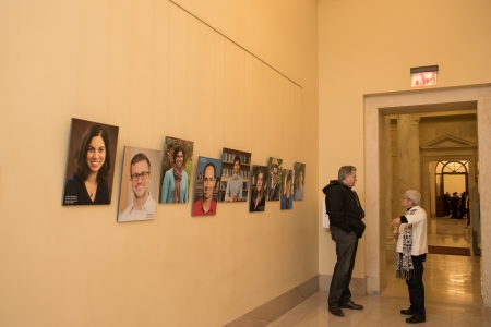 A man and woman stand in a hallway lined with portraits.