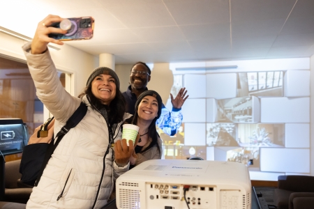 The librarians take a selfie in front of a video projection wall