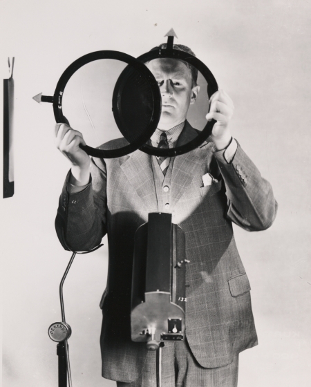 A black and white photograph of a man holding a set of filters