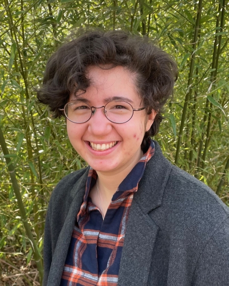 Avril Saavedra, wearing a gray collared top, smiles and looks at the camera