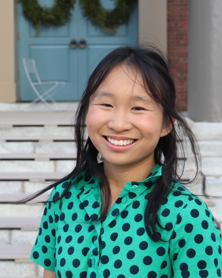 Jieyan Wang, wearing a dotted top, smiles and looks at the camera in front of Memorial Church