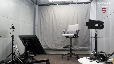Photograph of a white room with lights, chairs, and TV