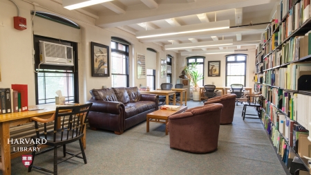 Photograph of a room filled with couches, chairs, desks, and books