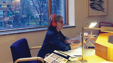 Eileen Myles works in the Poetry Room sitting with headphones on
