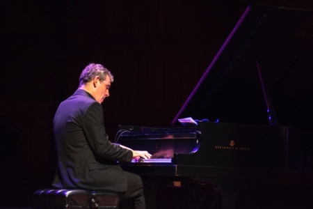 Achilleas Wastor plays the piano on a dark stage