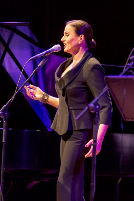 Karyofyllia Karabeti sings on stage in a black outfit
