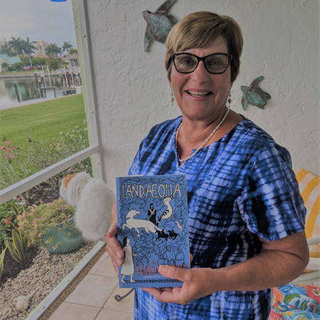 Woman holding book 'Land of Aeolia'