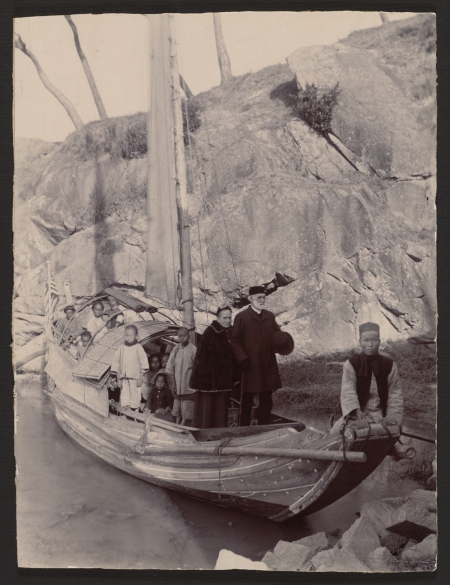 A group of people on a small boat that is in front of a cliff.