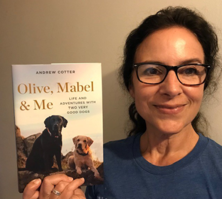 Woman holding up book 'Olive, Mabel, and Me'