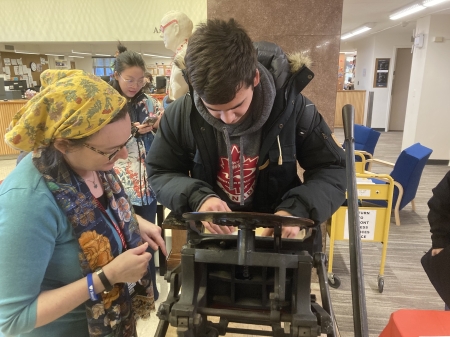 A student uses a tabletop printing press