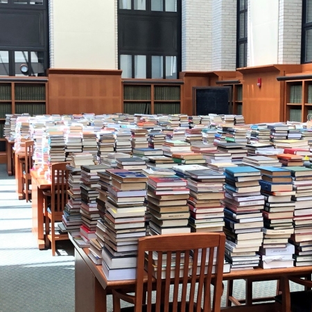 Stacks of books on tables in a large reading room