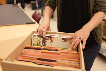 someone flips through a box of file folders at the Harvard University Archives