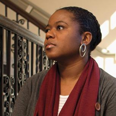 Kenvi Phillips wears a scarf and earrings and looks up and away from the camera