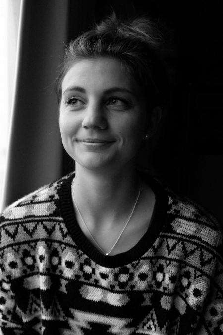 Marie Becker, wearing an ornate sweater, smiles away from the camera