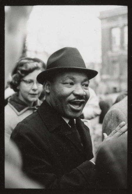 Dr. Martin Luther King, Jr. on the Harvard campus and smiling at passers-by, January 1965. 